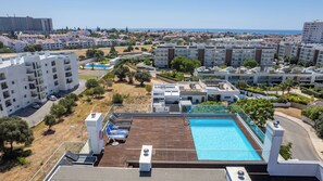 A residential area with a swimming pool, multiple apartment buildings, and a view of the sea. - Two-Bedroom Apartment with Pool and Balcony in Albufeira, Algarve (Albufeira)