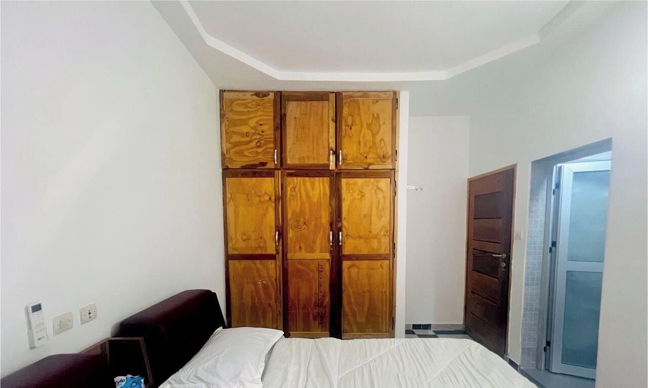 A bedroom with a bed, a wardrobe, and a door.