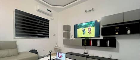 A modern living room with a flat-screen TV, a sofa, a coffee table, and a laptop.