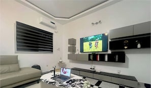 Una sala de estar moderna con una televisión de pantalla plana, un sofá, una mesa de centro y una computadora portátil.