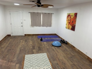 A room with a ceiling fan, exercise mats, a kettlebell, and a blue exercise ball. - Spacious 3-bedroom rock house with AC near the college in Perryton. (Perryton)