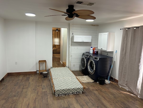 A laundry room with a washing machine, a drying rack, and a ceiling fan.
