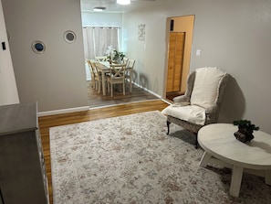 A living room with a dining area, a round table, and a chair.