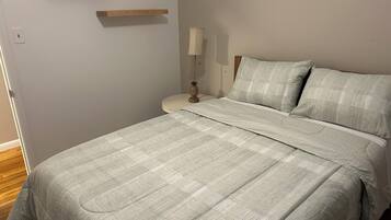 A bedroom with a bed, bedside table, lamp, and two wooden shelves.
