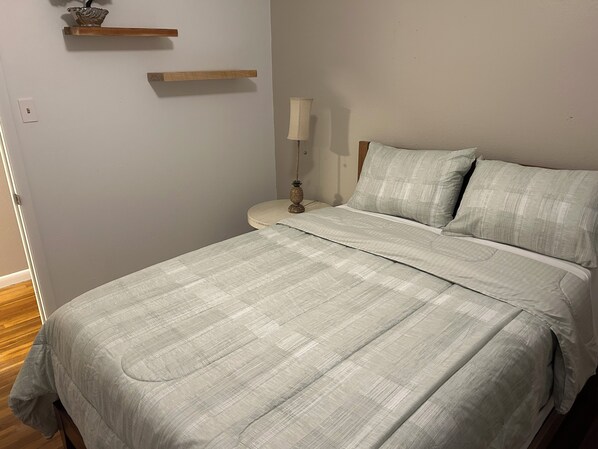 A bedroom with a bed, bedside table, lamp, and two wooden shelves. - Spacious 3-bedroom rock house with AC near the college in Perryton. (Perryton)