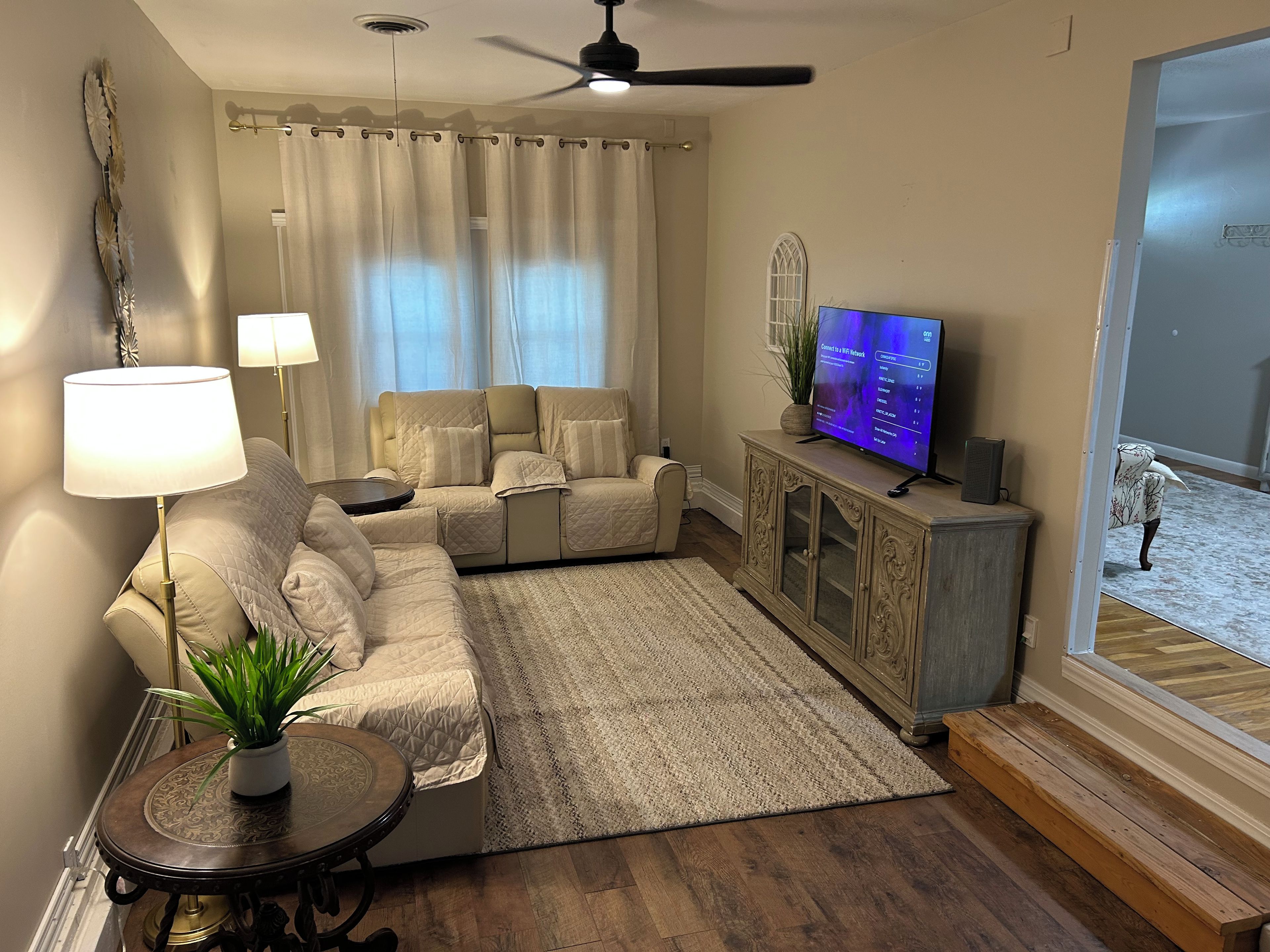 A living room with a sofa, a TV, a lamp, a plant, and a decorative mirror.