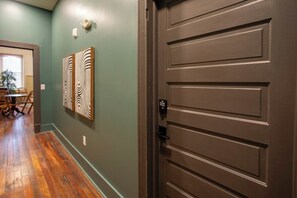 A hallway with a wooden floor, a brown door, and two wall-mounted artworks. - Downtown Florence Getaway - Shops, Cafés & Museums (Florence)