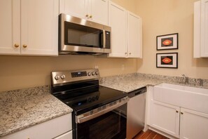 A kitchen with white cabinets, a stainless steel microwave, a black stove, and a dishwasher. - Downtown Florence Getaway - Shops, Cafés & Museums (Florence)