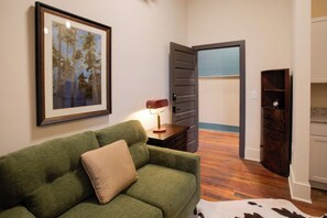 A room with a green sofa, a framed picture on the wall, a lamp, and a wooden cabinet.