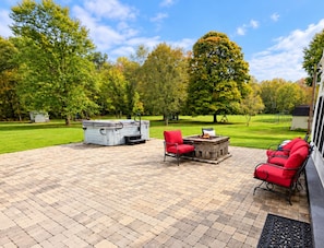 An outdoor patio with a fire pit, red chairs, and a stone table. - Relaxing 2-bedroom pool house - Bedford, IN. Easy drive for IU Football (Bedford)