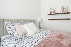 A neatly arranged bedroom with a bed, pillows, a bedside lamp, and wall-mounted decor. - #1 Anaheim Gem-Disney-Stadium-Honda Center-Pool-Spa-BBQ-Park (Anaheim)