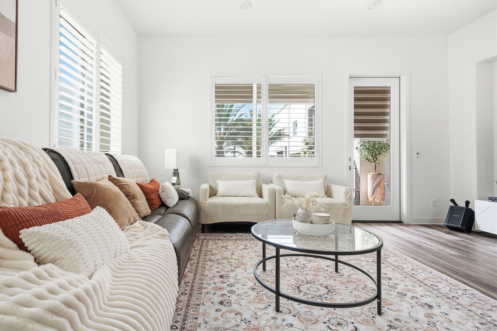 A living room with a sofa, two armchairs, a coffee table, and a patterned rug.