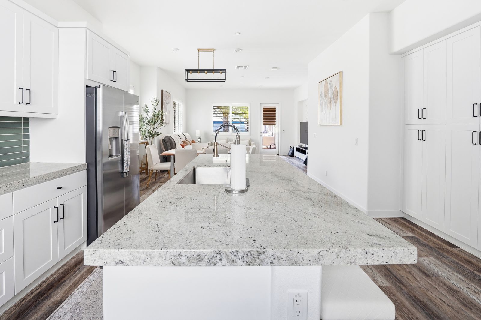 A modern kitchen with white cabinetry, a granite countertop, and a stainless steel refrigerator.