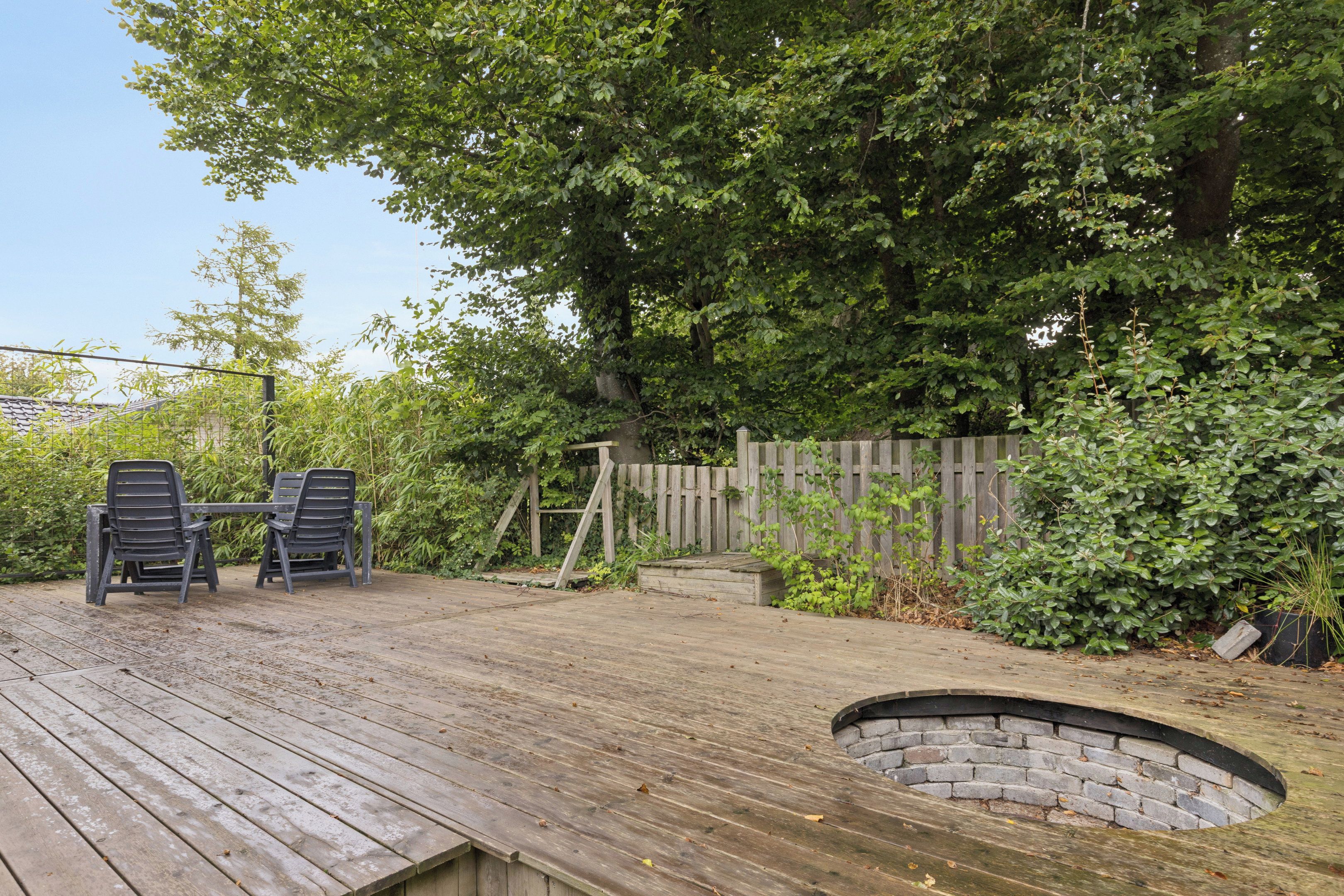 A wooden deck with two chairs and a small brick structure.