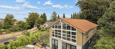 Il s'agit d'une propriété résidentielle dotée d'une grande façade vitrée, d'un toit en pente et d'une cour arrière avec un espace patio.