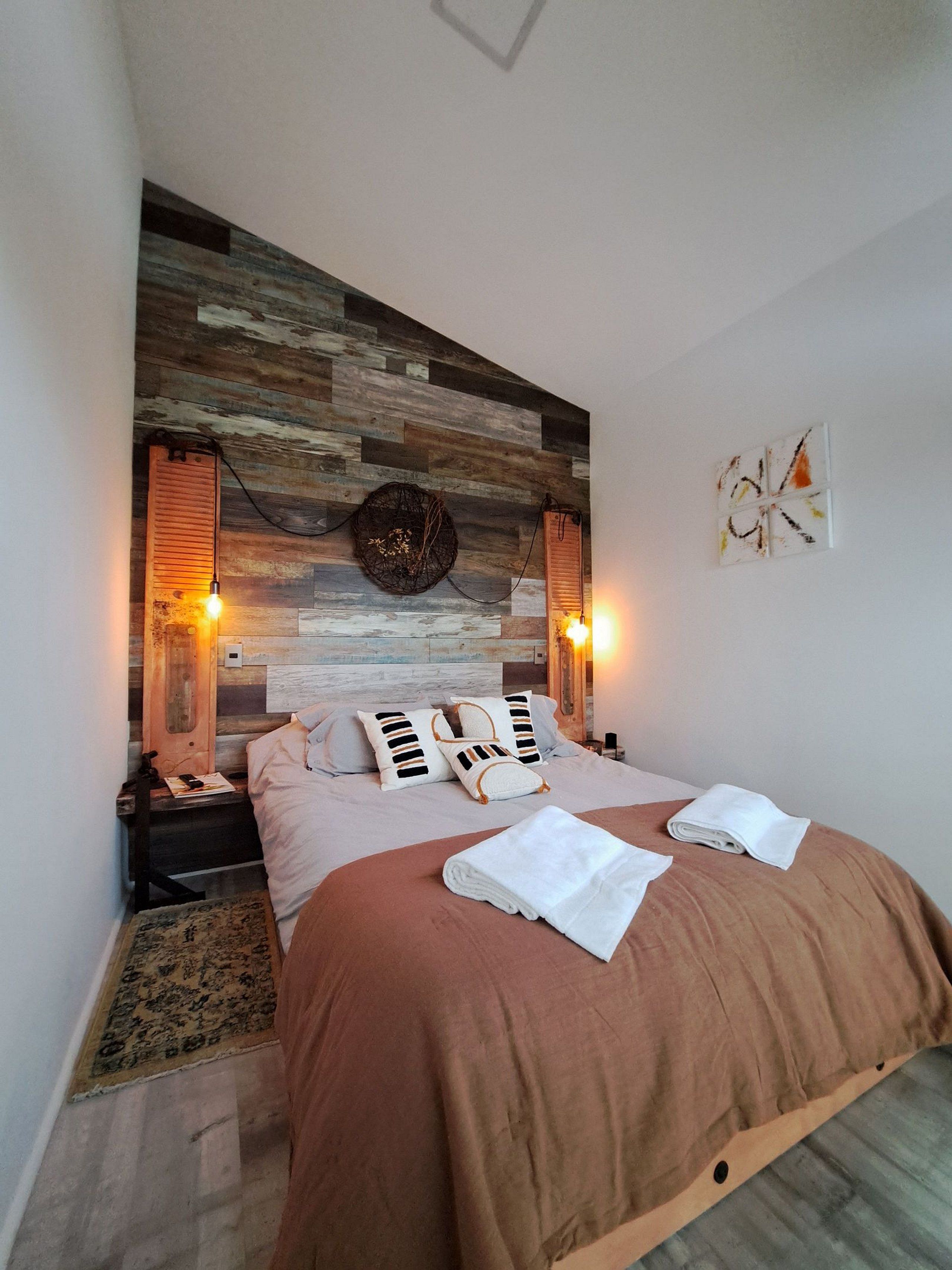 A bedroom with a wooden headboard, two bedside lamps, a bed with a brown cover, and a small rug.
