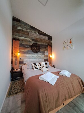 A bedroom with a wooden headboard, two bedside lamps, a bed with a brown cover, and a small rug. - Okeyloft 4 Coyhaique (Coyhaique)