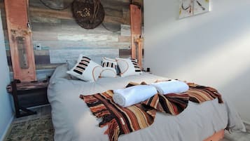 A modern bedroom with a wooden headboard, a bed with striped pillows, and a decorative wall piece.