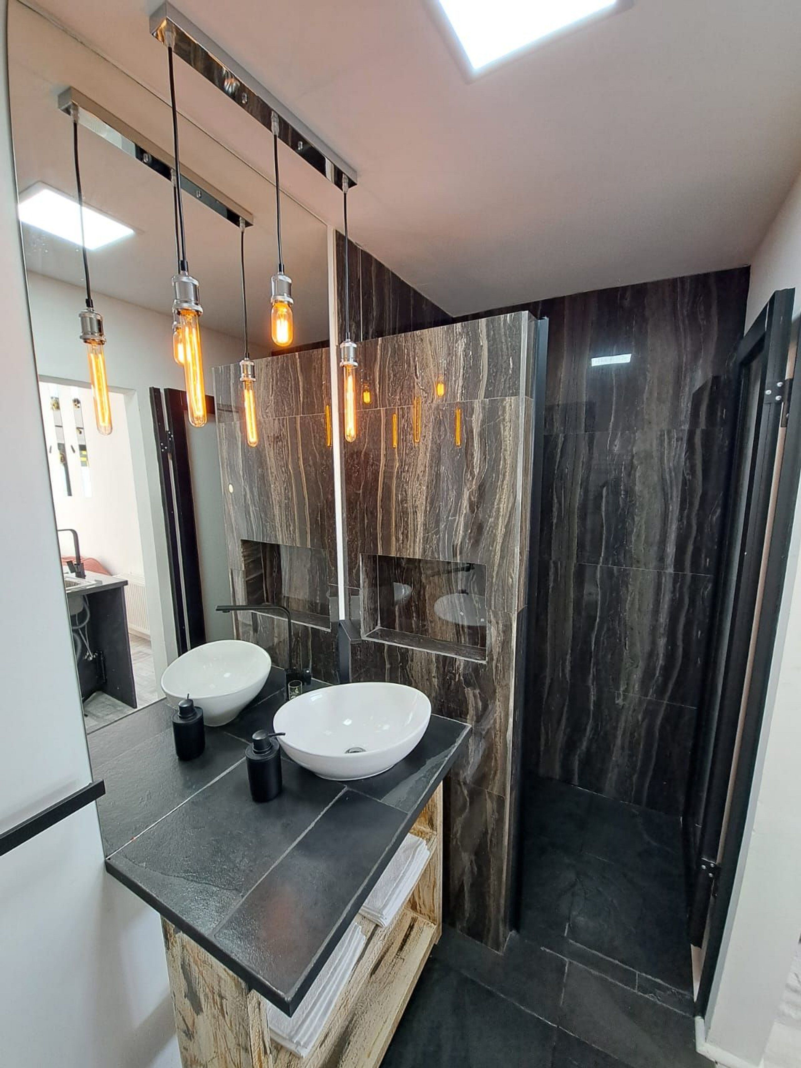 Un baño moderno con dos lavamanos, un espejo grande y un tragaluz.
