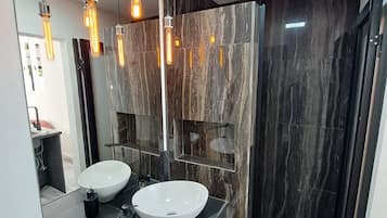 Un baño moderno con dos lavamanos, un espejo grande y un tragaluz.