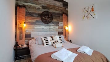 A bedroom with a wooden headboard, two bedside lamps, a bed with a brown cover, and a small rug.