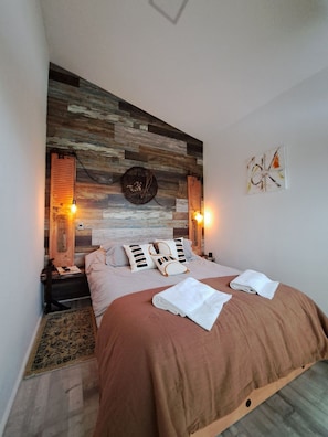 A bedroom with a wooden headboard, two bedside lamps, a bed with a brown cover, and a small rug. - Okeyloft 4 Coyhaique (Coyhaique)