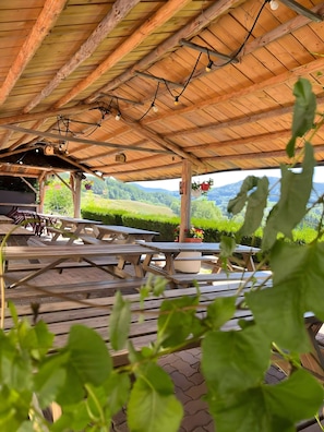 Un pavillon extérieur en bois, doté de tables de pique-nique et de guirlandes lumineuses.
