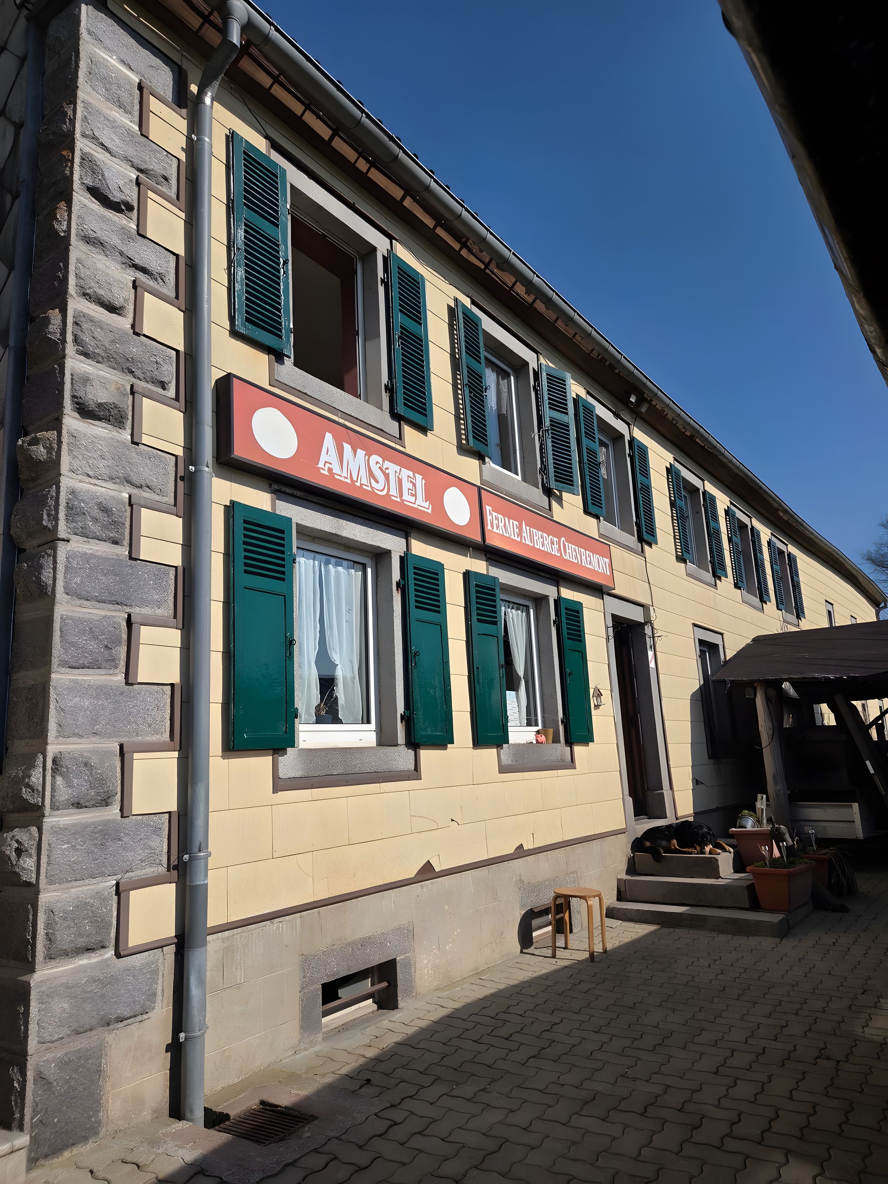 Un edificio con un letrero que dice 'AMSTEL' y 'FERME AUBERGE CHEVROLET'.