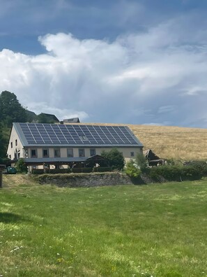 A house with a solar panel roof and a stone wall in front. - Bed and Breakfast 'Chambre Noëlle' with Mountain View and Shared Terrace (Orbey)