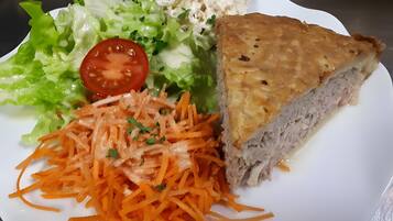 A plate with a slice of pie, a salad, and shredded carrots.