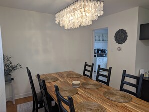 A dining room with a wooden table, black chairs, woven placemats, and a unique chandelier. - Comfortable 3BR getaway 5 min from Midway Airport and 15 min to Downtown. (Chicago)