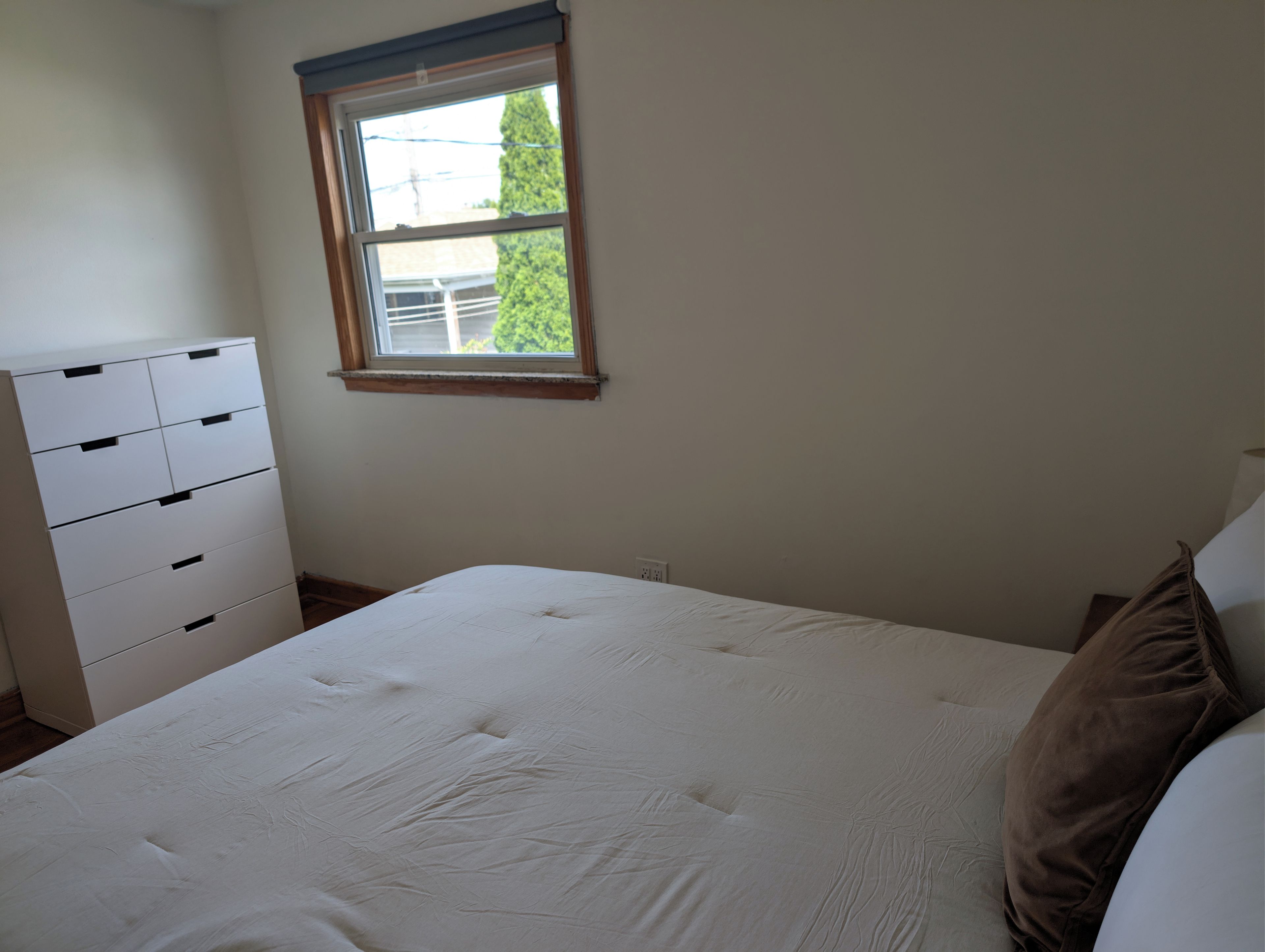 A bedroom with a bed, a dresser, and a window.
