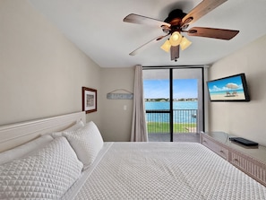 Ein Hotelzimmer mit Bett, Deckenventilator, Fernseher und einem Balkon mit Meerblick.