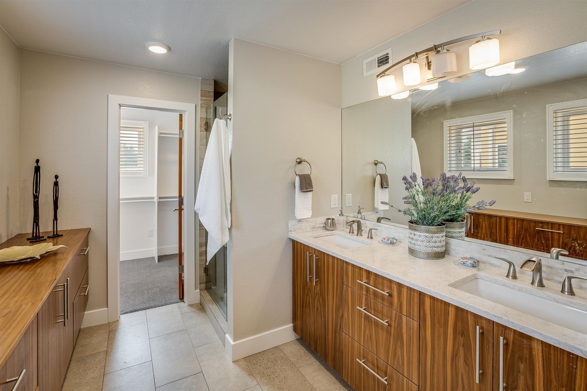 A modern bathroom with a large vanity, a walk-in shower, and a large mirror.