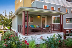 A covered porch with a seating area, a white exterior wall, and a number '1231' on the building. - Festival-Season Basecamp, Walk to Pearl St Theaters (Boulder)