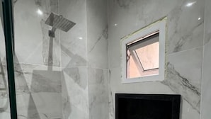 A bathroom with a shower, a small window, and a built-in TV. - UMARI RESERVA HOTEL (Benevides)
