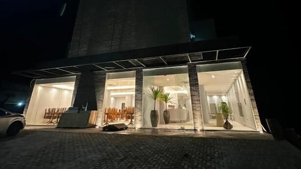 A modern building with a large glass facade, a paved entrance area, and a car parked outside. - UMARI RESERVA HOTEL (Benevides)