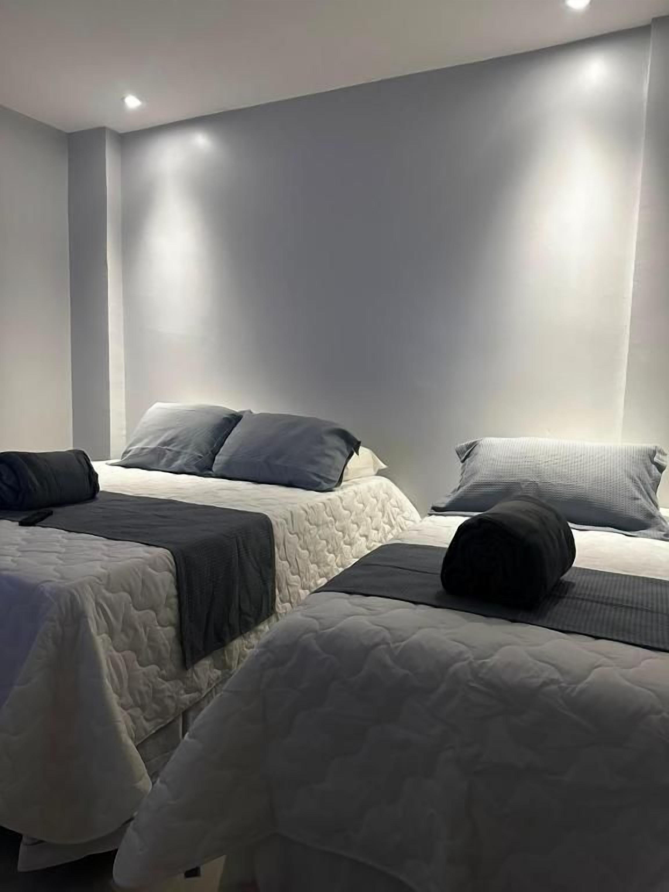 Quarto de hotel com duas camas, cada uma com travesseiro e cobertor.