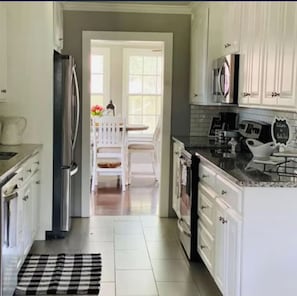 A kitchen with white cabinets, a stainless steel refrigerator, a coffee maker, and a microwave.