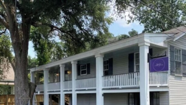 A two-story building with a covered patio area and a fenced yard.