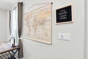 Eine Weltkarte an der Wand, ein Lichtschalter und ein Schild mit der Aufschrift 'PIN WHERE YOUR FROM!'