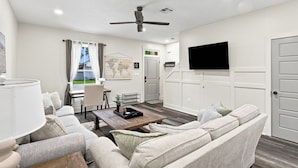 Un soggiorno moderno con un divano, un tavolino, una TV a parete e una ventola a soffitto.