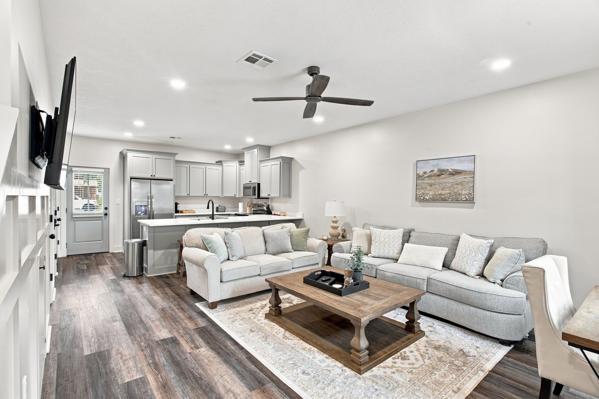 A modern living room with a sofa, coffee table, and a kitchen in the background.