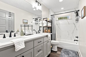 Een moderne badkamer met een wastafelmeubel met dubbele wastafel, een toilet en een bad.