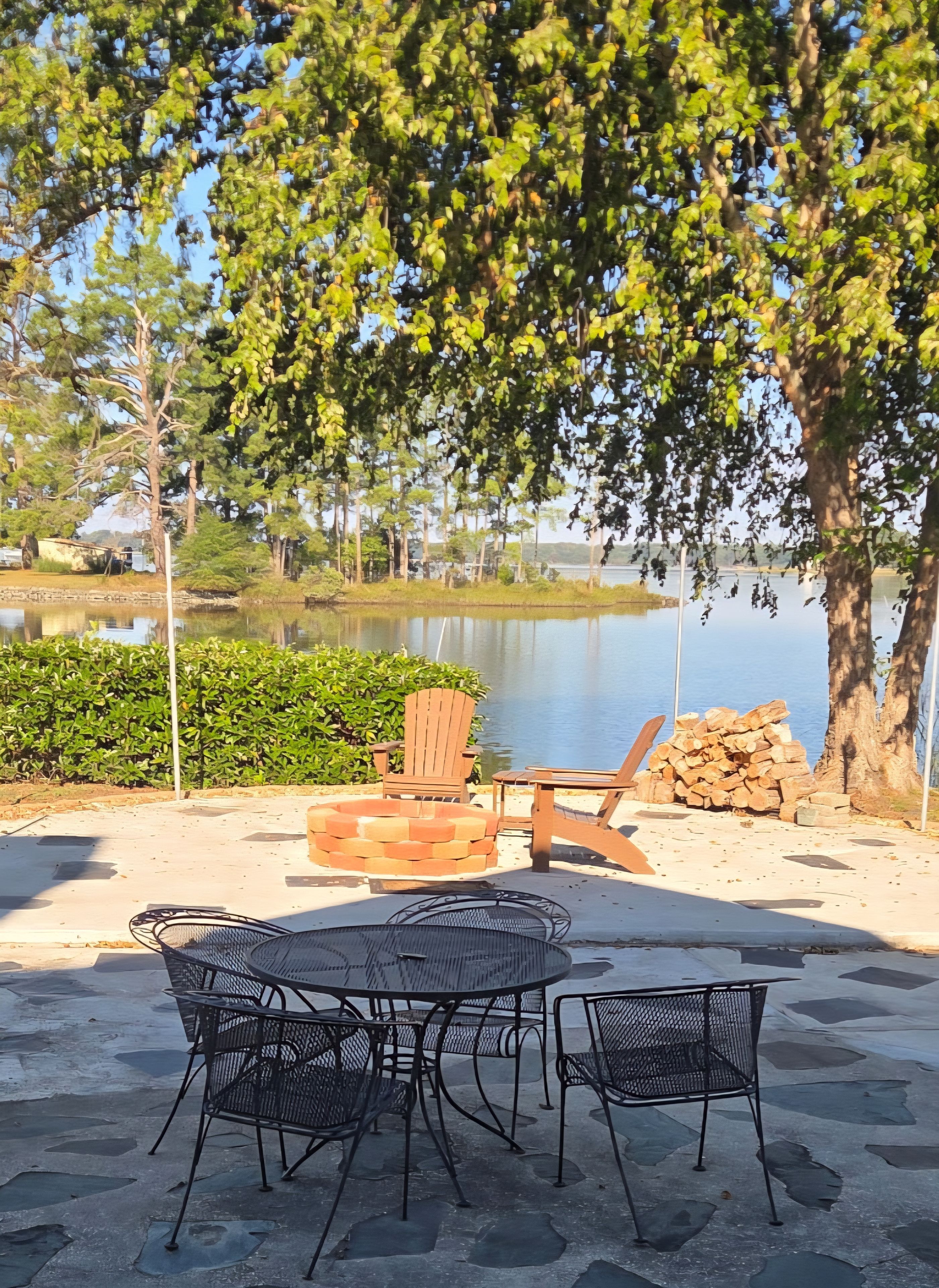 An outdoor seating area with a fire pit, chairs, and a view of a lake.