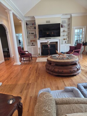 A spacious living room with a fireplace, a large flat-screen TV, and a round coffee table. - Beautiful Waterfront Property, Boat Dock, Covered Carport and Wonderful Sunsets (Lancaster)