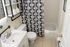 A bathroom with a toilet, sink, and bathtub. - Graceful Stays: Cozy 1BR in the Highlands (Louisville)