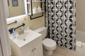 Une salle de bain avec un lavabo blanc, des toilettes et un rideau de douche à motifs géométriques.