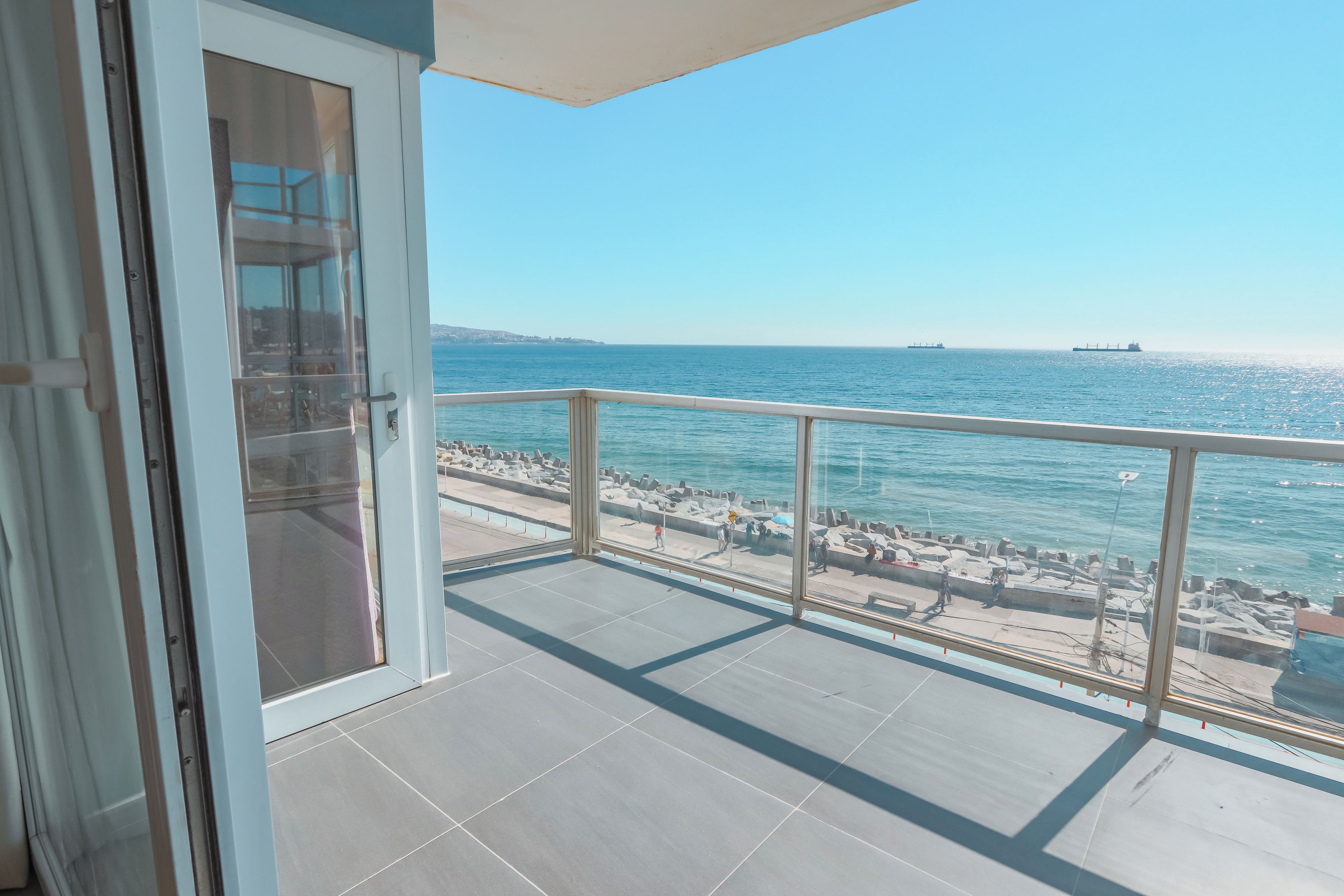 Ein Balkon mit freiem Blick auf das Meer, einem Fliesenboden und einer Glastür.