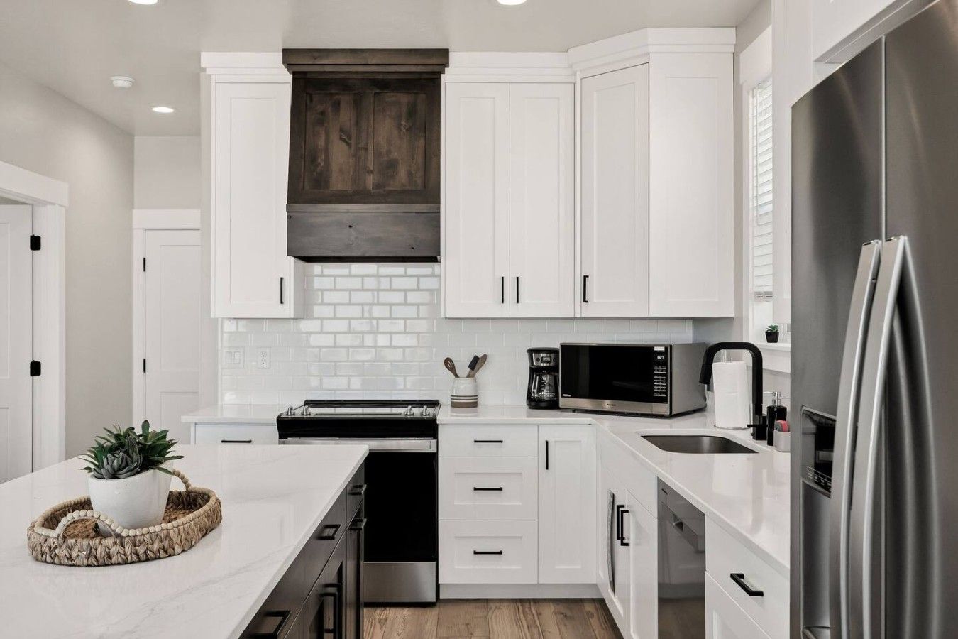 Una cocina moderna con muebles blancos, un refrigerador de acero inoxidable y un microondas integrado.